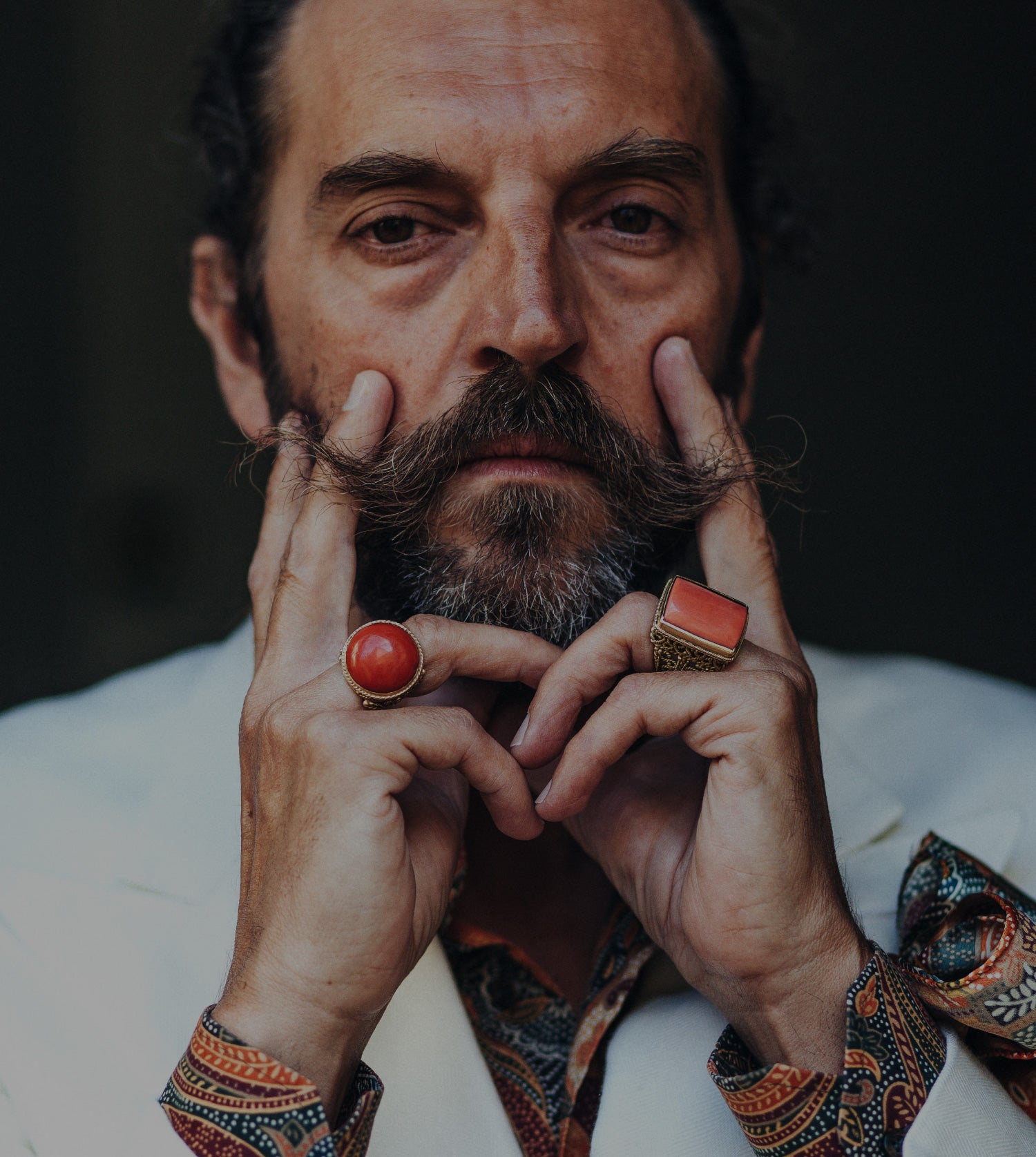 Massimo izzo si tocca i baffi con anelli di Massimo Izzo in oro giallo 18kt e corallo nelle mani